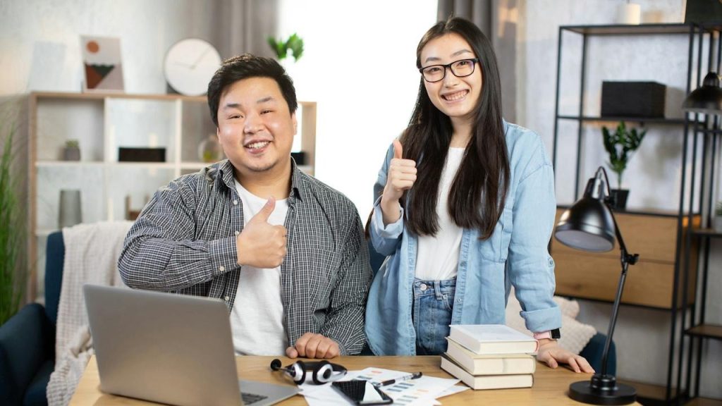 A couple working and giving a thumbs up gesture.
