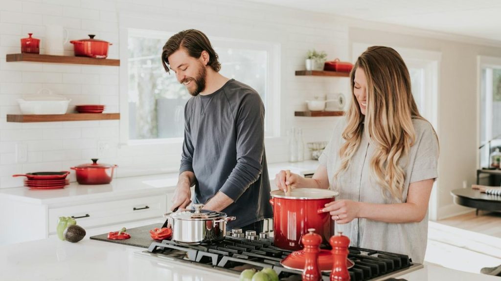 A couple cooking together in a kitchen.
