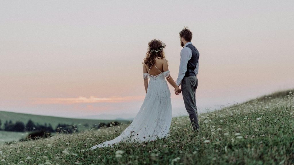 A married couple standing in a field filled with flowers.