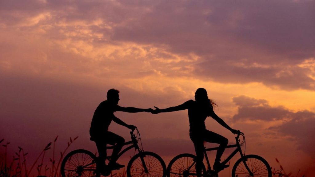 A couple riding bicycles at dusk.