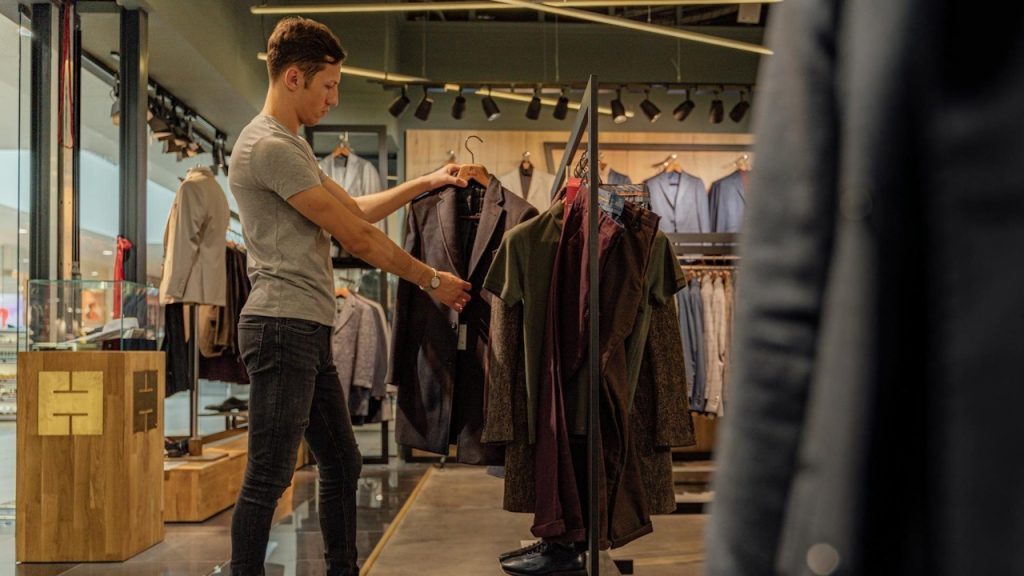 A man looking at a suit jacket in a clothing store.