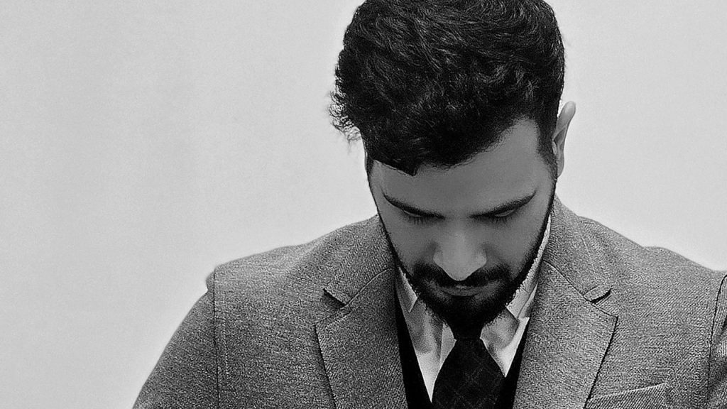 Elegant and bearded man in a gray blazer.
