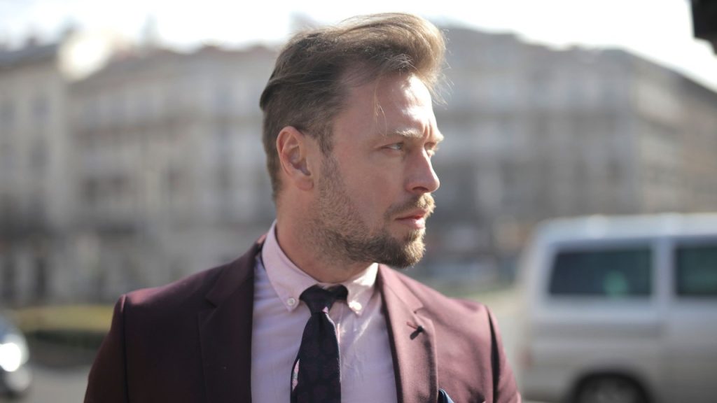 A confident businessman standing on a street in a city.
