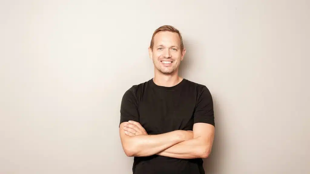 A smiling man with arms crossed on a gray background