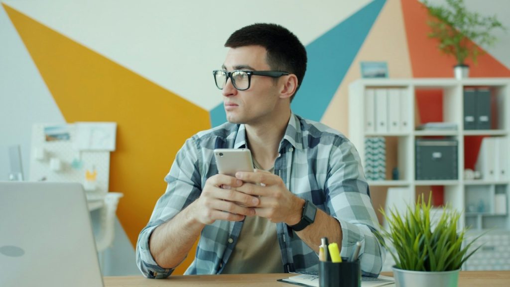A man holding a phone looking confused