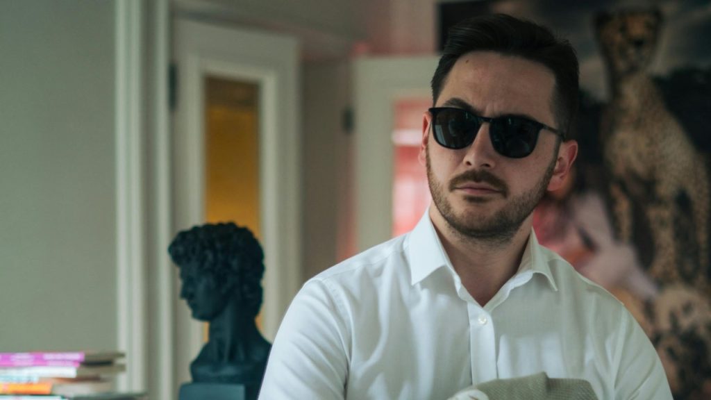 A confident bearded man in sunglasses in a museum.