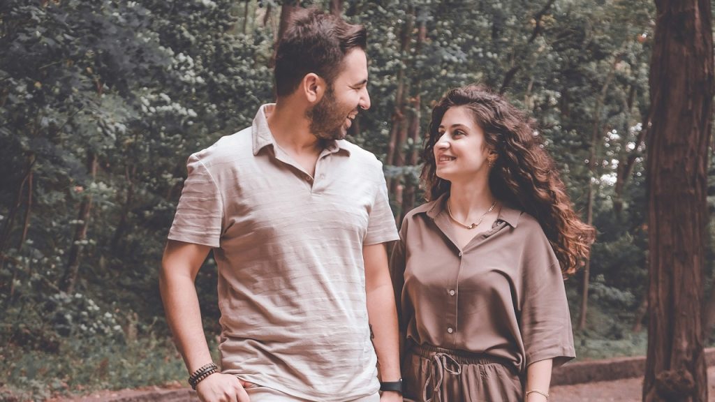 A man and woman walking on a path in the woods.