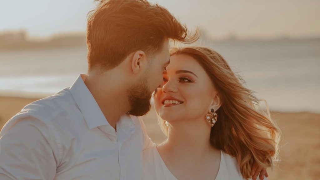 A man and a woman standing next to each other on a beach.