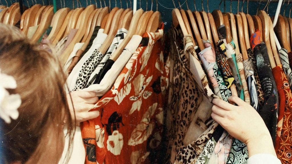A woman rifling through dresses in her closet.