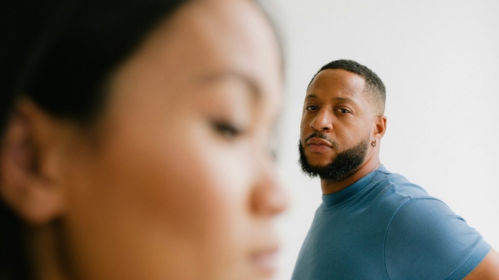 A bearded man looking sideways at a woman.