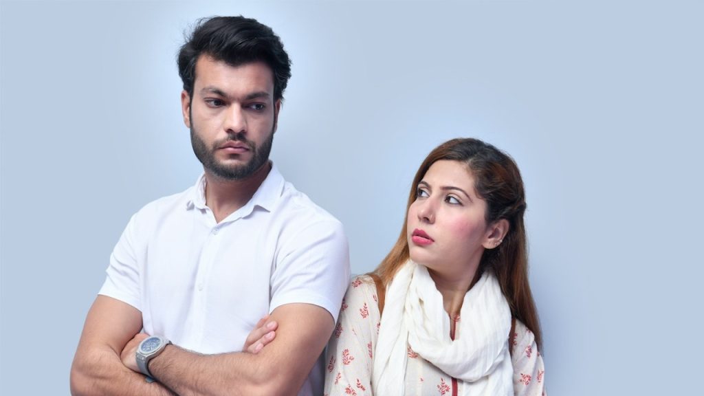 A woman looking at a bearded man who has his arms crossed across his chest.