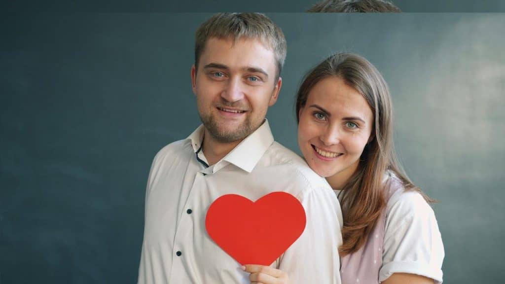 A Couple holding a red heart symbol.