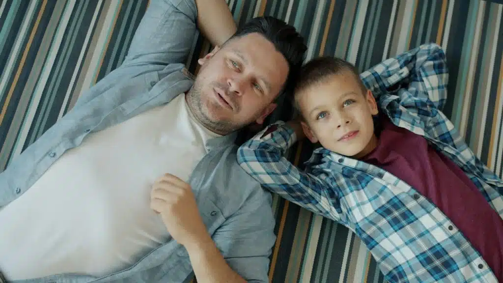 A man lying on the ground wiht his son.