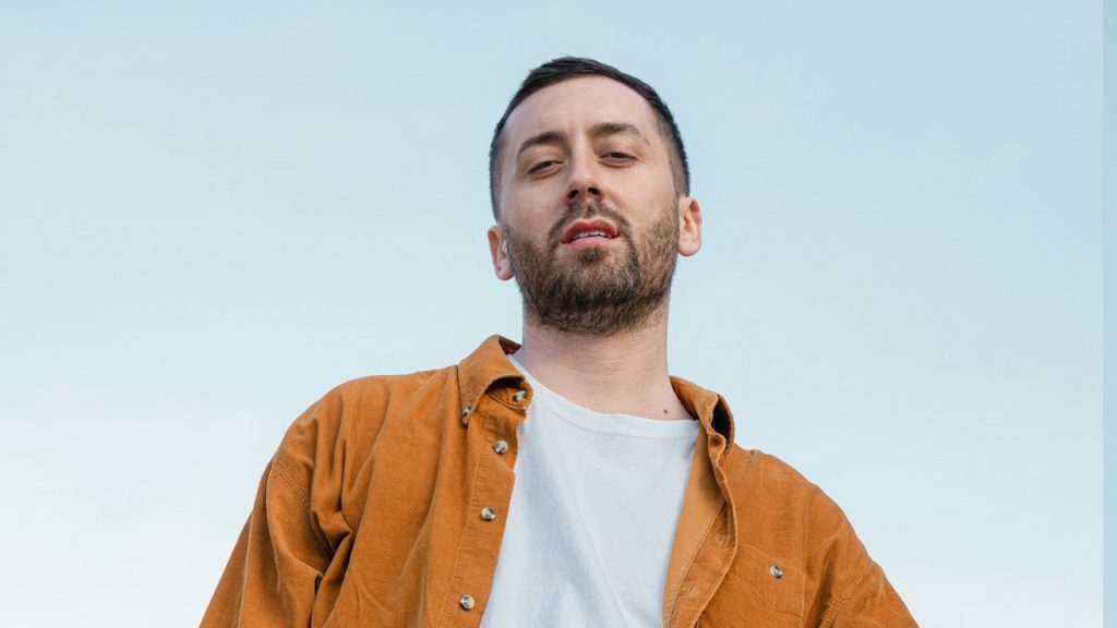 A man posing confidently with hands in pockets.