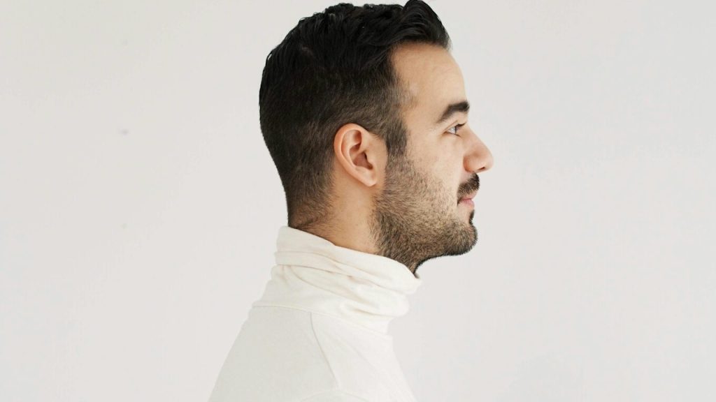 A side view of a man wearing a white top.