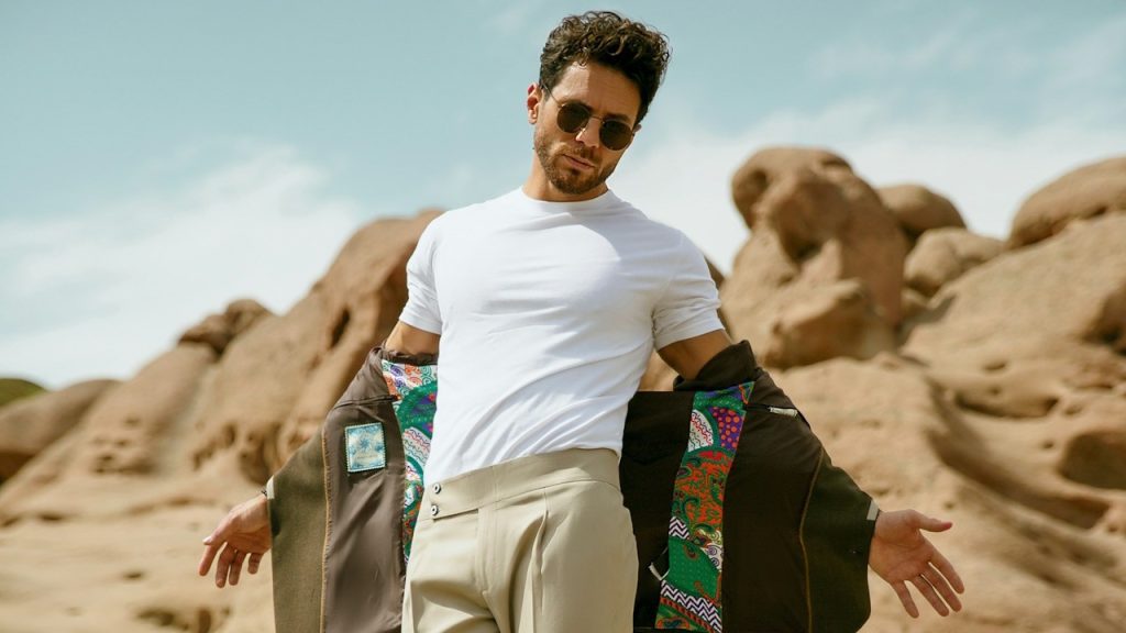 A man dressed up nicely is standing in the sand.