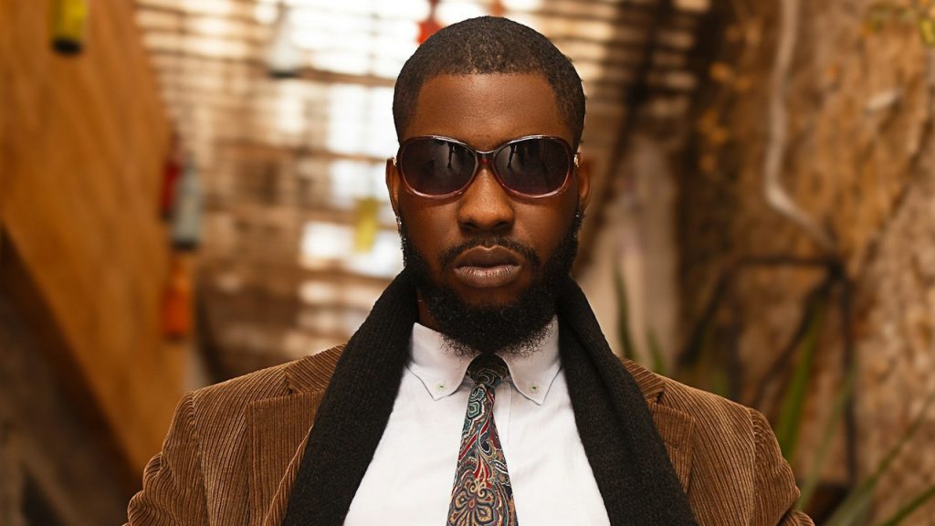 A man in a stylish outfit with sunglasses and a floral neck-tie.