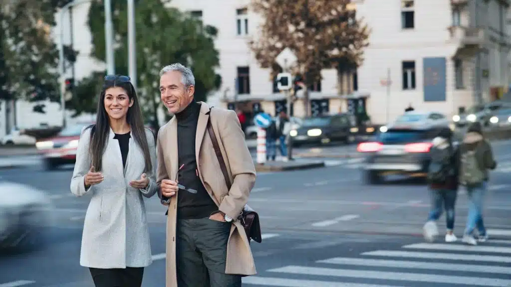 A mature couple talking and standing on a pavement by the street.