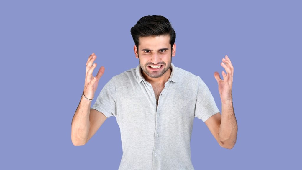 An angry man gesturing with his hands and baring his teeth.
