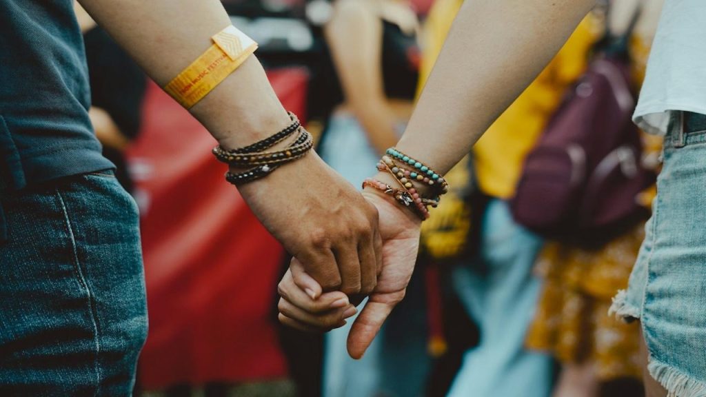 A man and a woman holding hands in a crowd