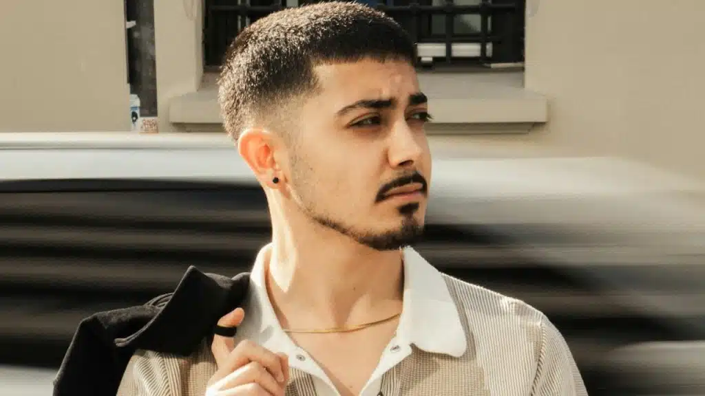 A man in a white polo-shirt is walking down the street while holding a jacket.