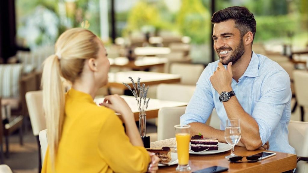 A couple having desert and juice while they are sitting in a restaurant.