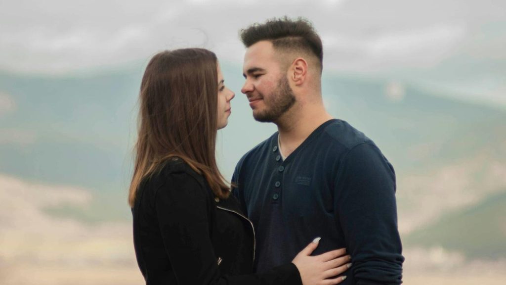 A couple standing close looking in the eyes of each other.