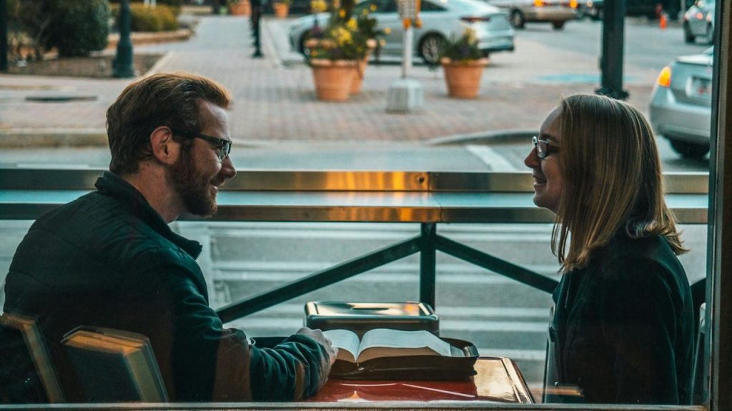 A couple reading a book while sitting together in a library.