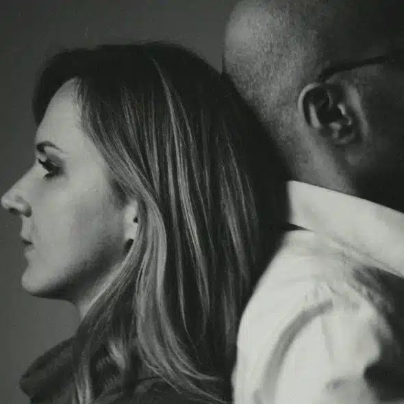 A black and white profile photo of a woman and man leaning back to back.