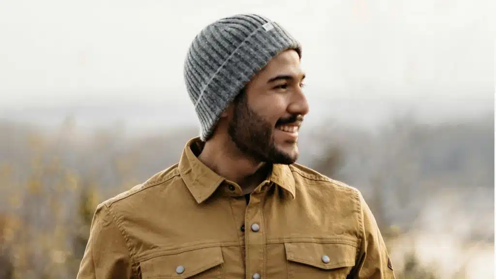 A man with a beard wearing a brown jacket.