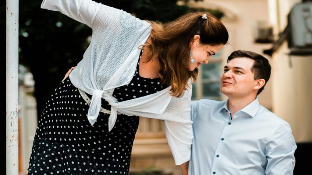 A man in a blue dress shirt and a woman in a black-and-white polka-dot dress.