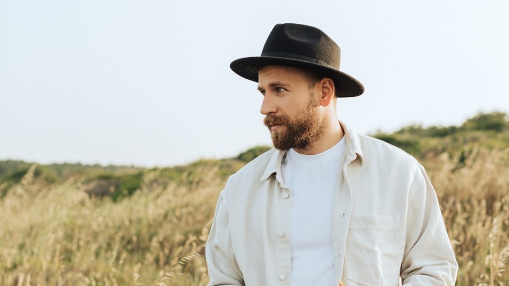 A man in a hat standing in a field.