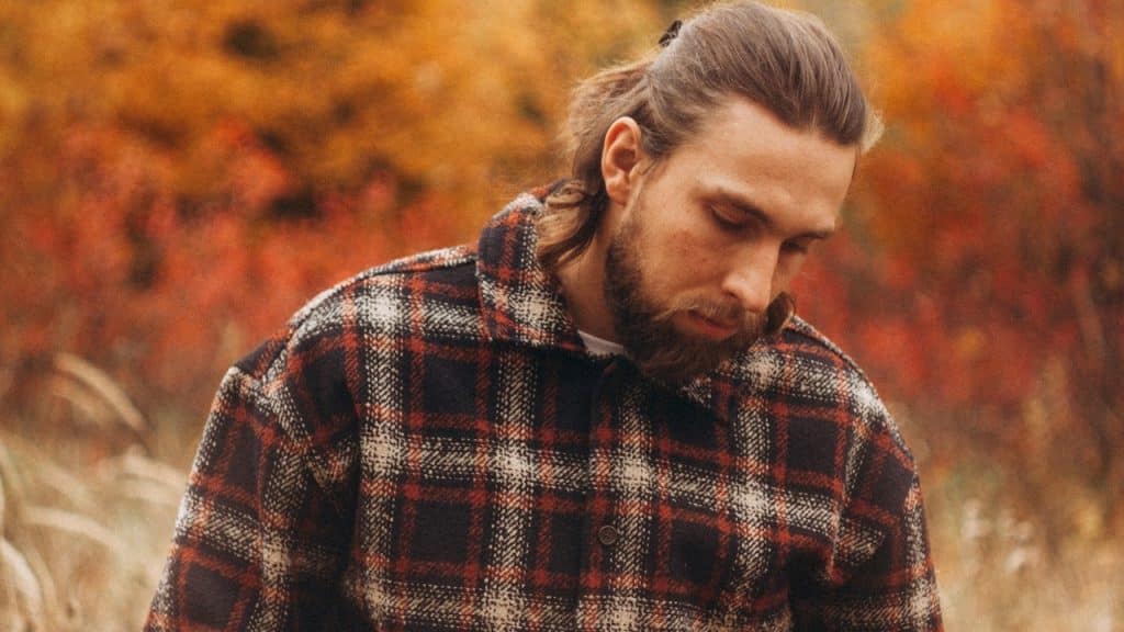 A man in a plaid shirt in an autumn forest.