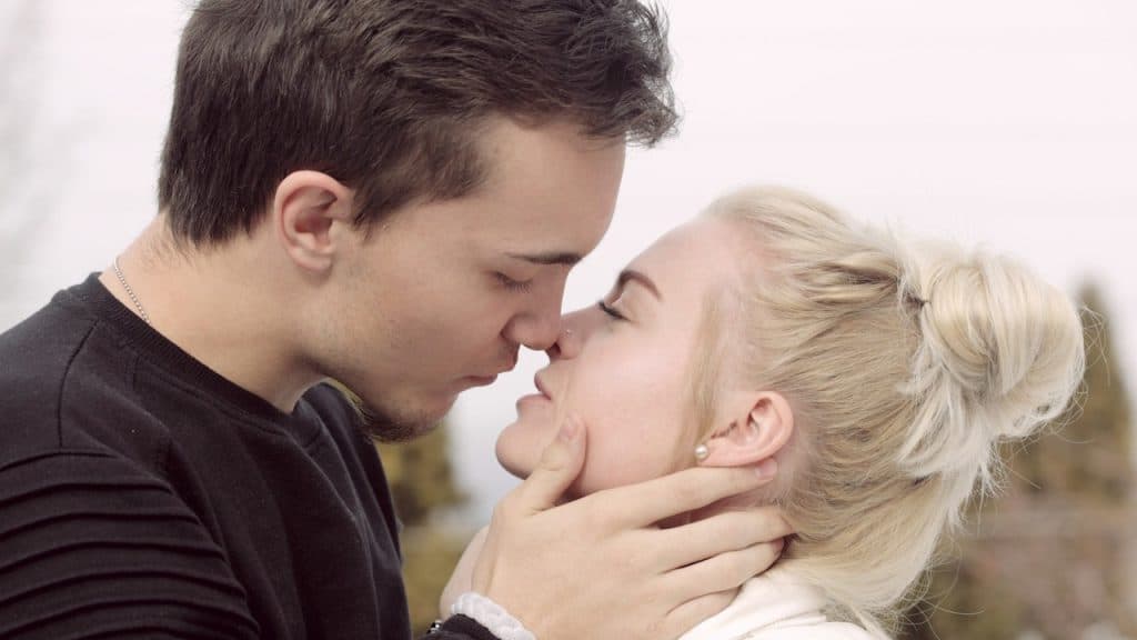A man wearing a black top is about to kiss a woman.