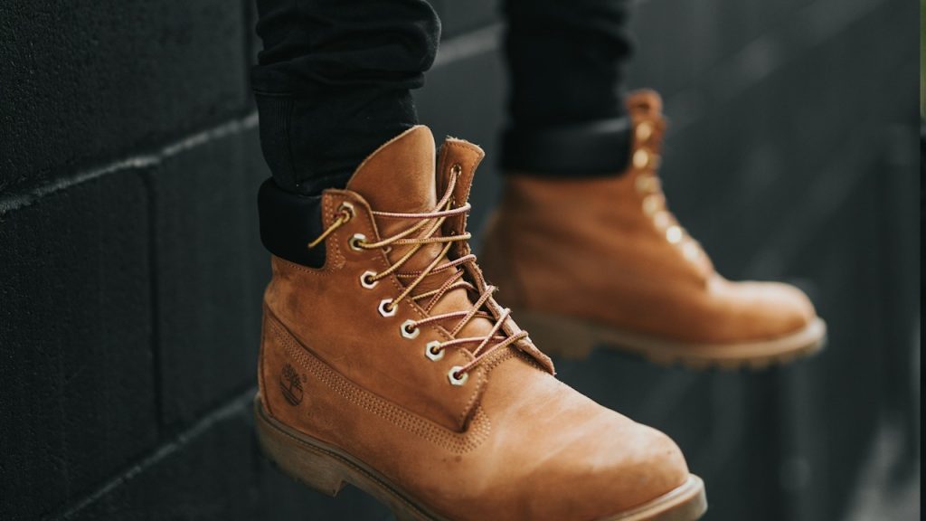 A person wearing a pair of brown Timberland leather work boots.
