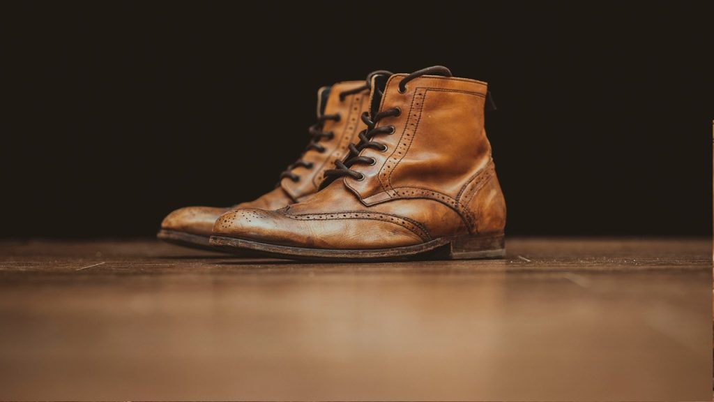 A pair of brown-leather booties on a brown surface.