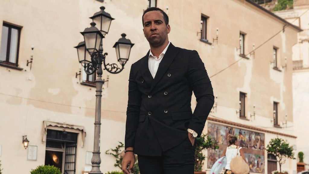 A man wearing a black double-breasted suit.