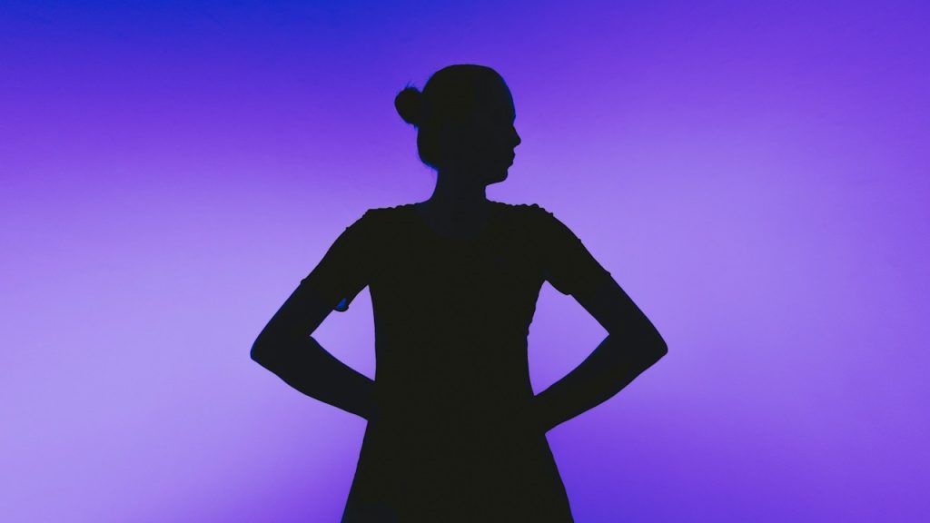 Silhouette of a woman with hands on hips.