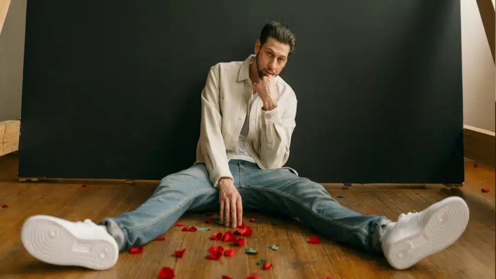 A man sitting on the floor with petals of roses.