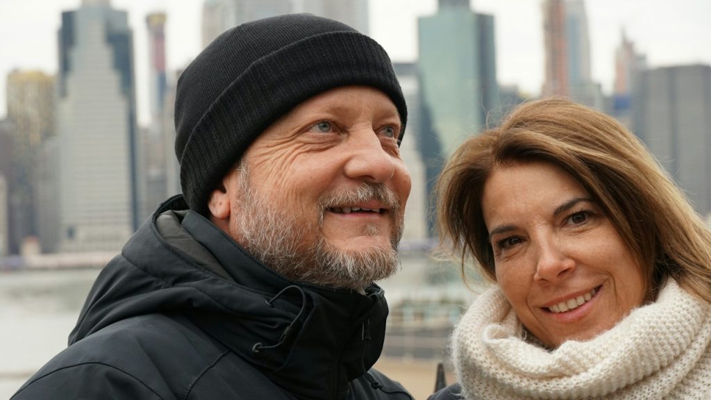 A man and a woman wearing coats are standing near water.