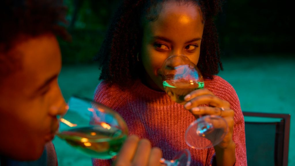 A woman looking at her boyfriend while they are having wine together.