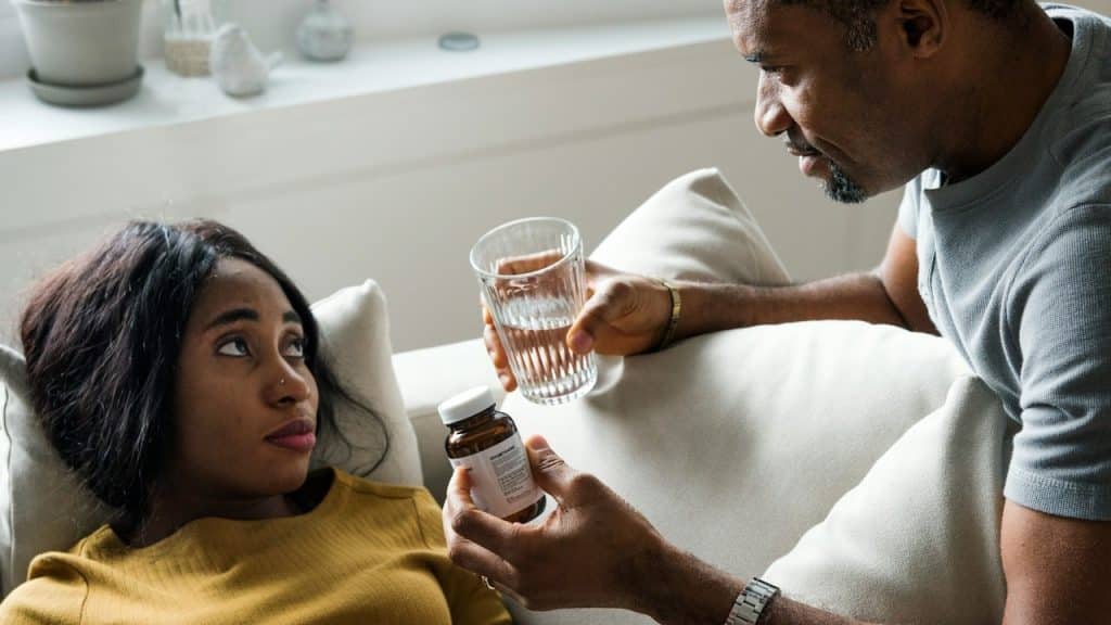 A man giving supplements to his tired wife.