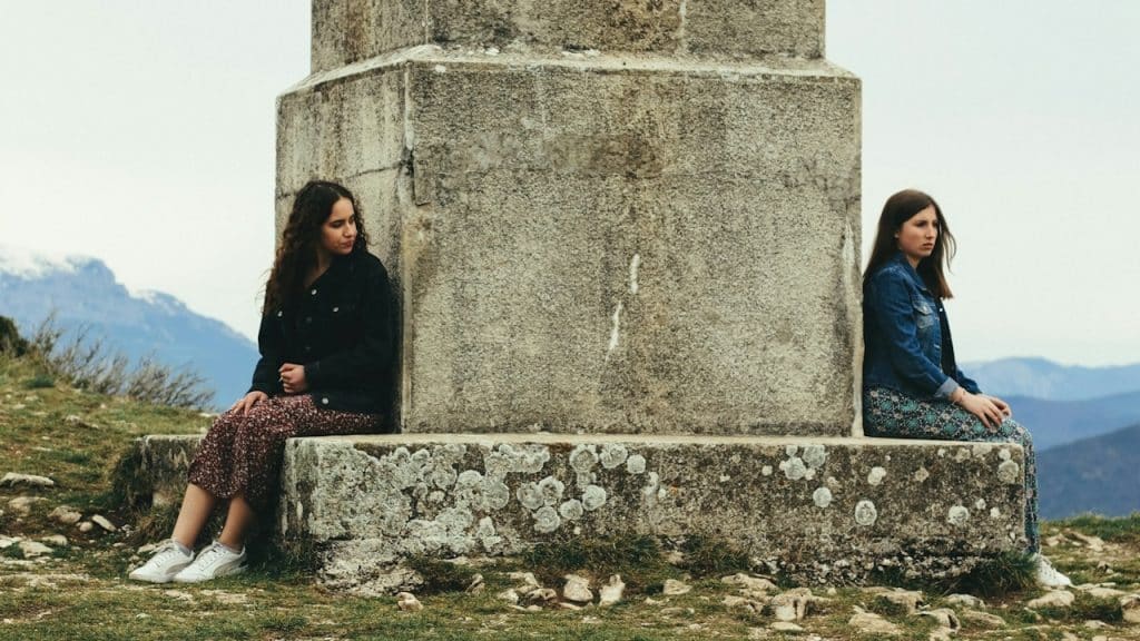 A woman in a black jacket is sitting beside a woman in a blue jacket.