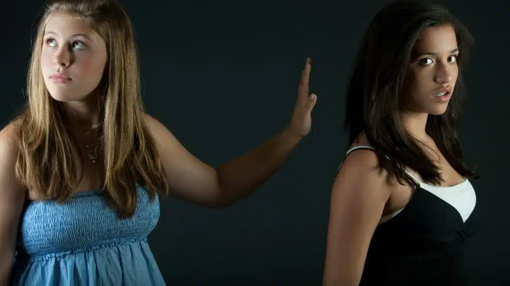 A girl in a blue frock is stopping a girl in a black dress.