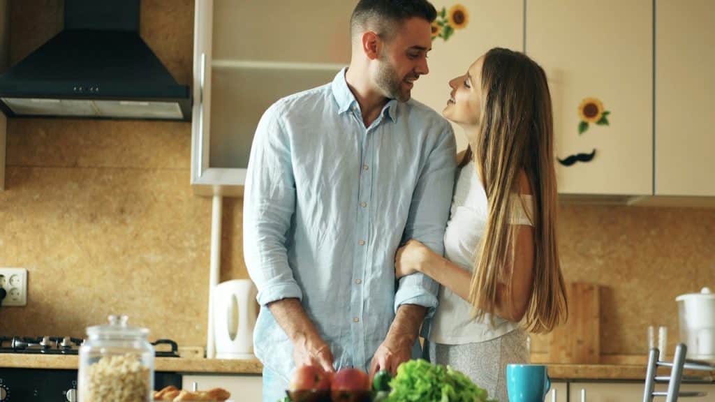A happy couple making meal together in their kitchen.