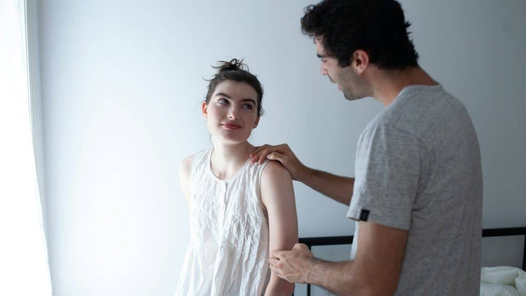 A man touching her wife’s shoulder.