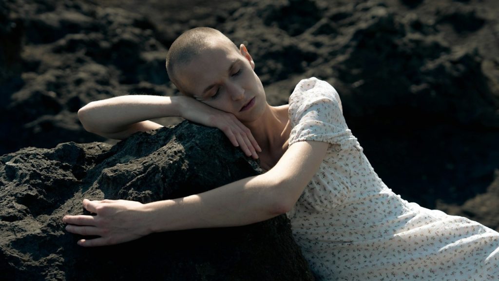A woman lying on the top of a large rock.