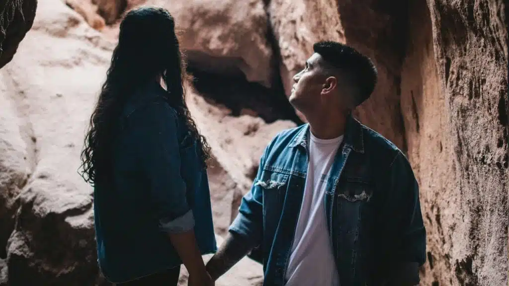 Couple in denim jackets holding hands in a rocky canyon.