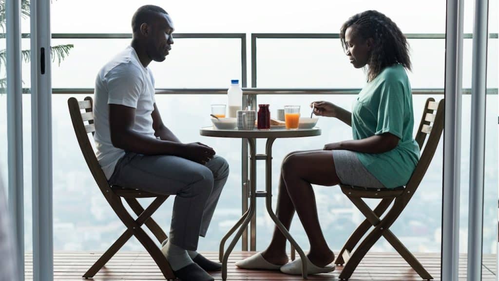 Man and woman dining at a table on a balcony.