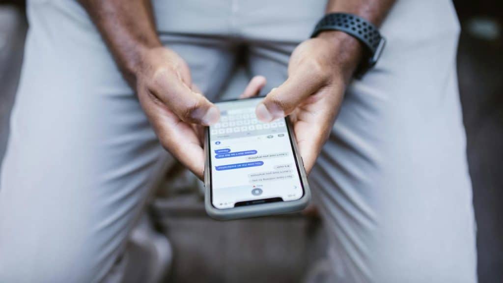 A person holding a smartphone and typing a text message.